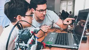 Coder Dojo Junge mit Lehrer, Laptop und Roboter